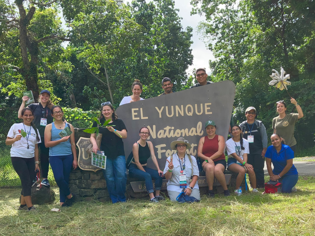 A group of 14 people in front of the El Yunque National Forest sign
